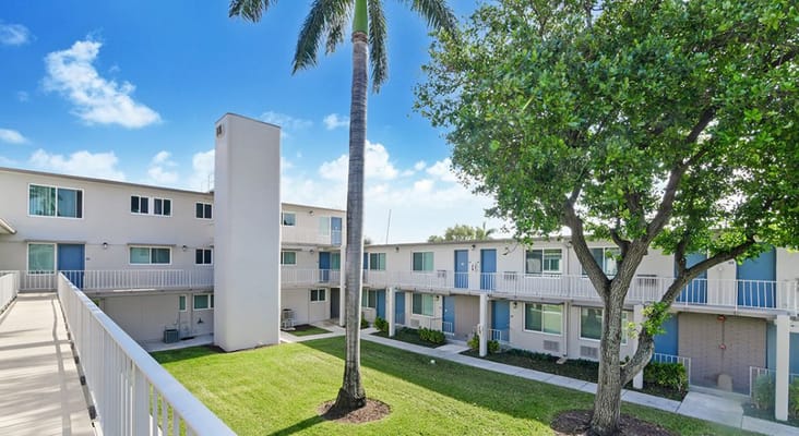 View of the courtyard at Gateway Terrace Senior Apartments with palm trees and greenery.
