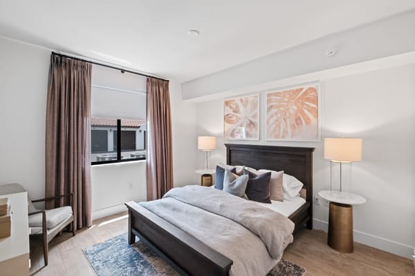 Well-furnished bedroom with a bed, side tables, and large window