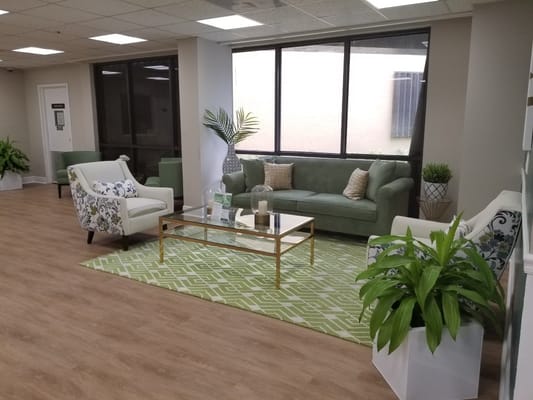 Living room with green couches and floral chairs in a senior living facility