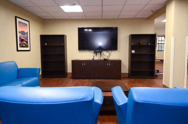 Bright common area with blue chairs and a TV