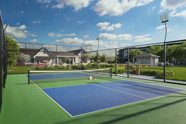 Tennis court with two blue courts and green surroundings
