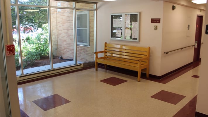 Bright hallway with a wooden bench and large windows