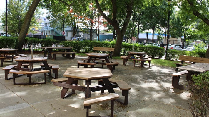 Outdoor seating area with picnic tables under trees