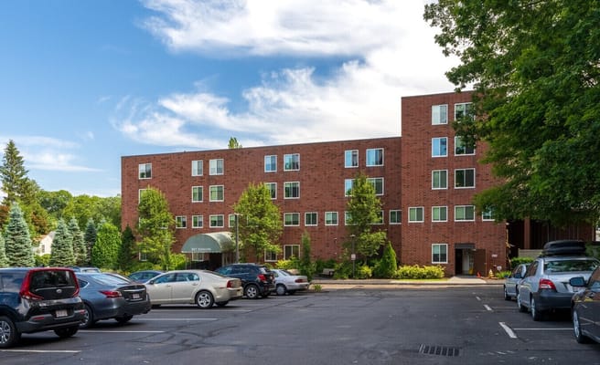 Brick building of Bet Shalom Senior Apartments with parked cars.