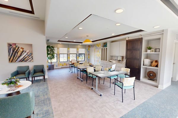 Bright common area with chairs and tables for residents