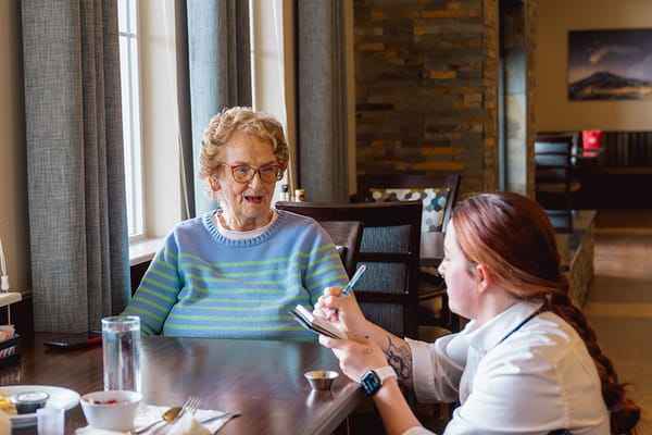 A nurse taking notes while conversing with a resident