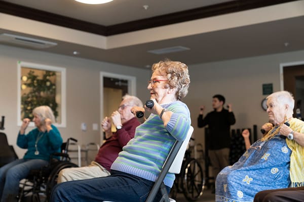Residents participating in a seated exercise class indoors