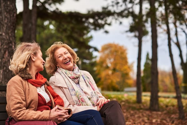 Two women enjoying each other's company on a bench outdoors