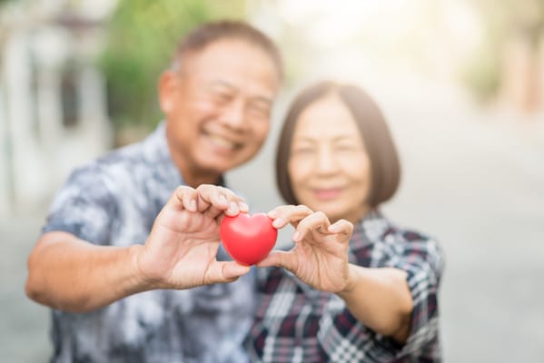 Couple holding a red heart in an outdoor setting
