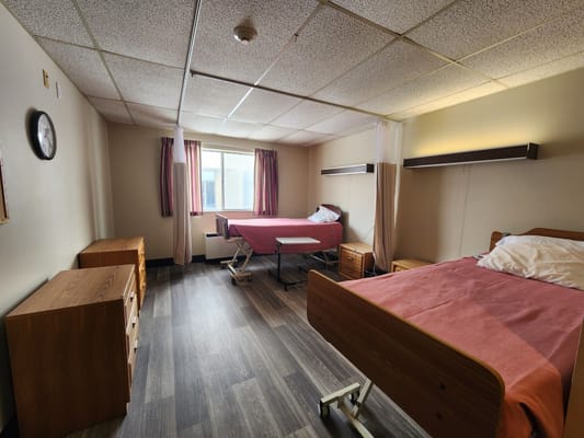 A shared resident room with two beds and furniture