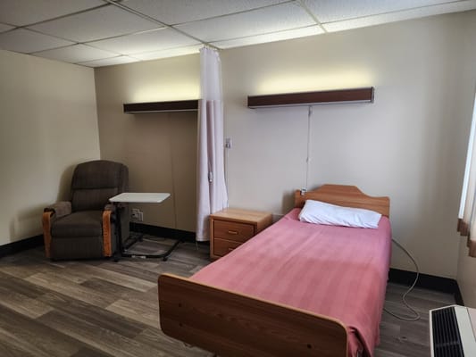 Bright interior of a resident room with a bed and chair