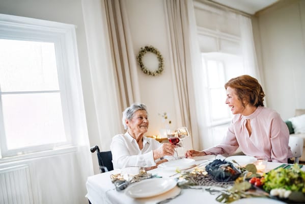 Two women toasting with drinks at a dining table