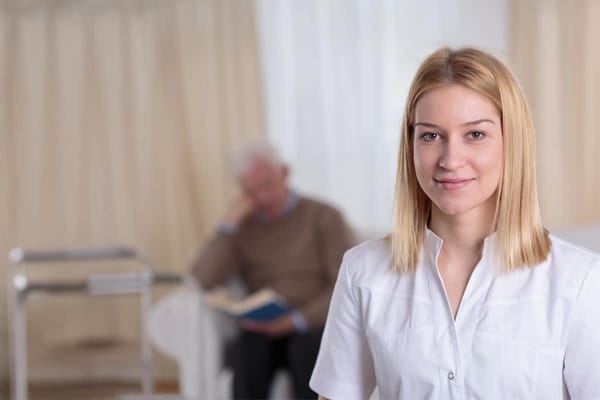 A caregiver smiling with a resident in the background