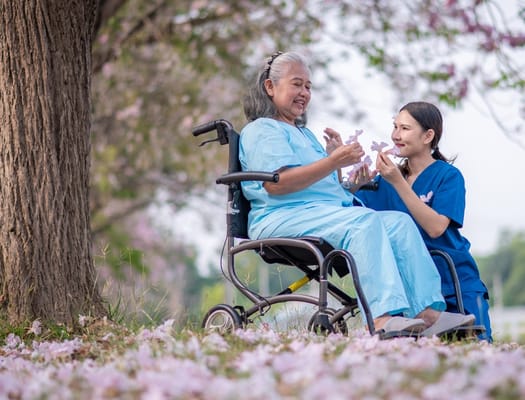 Resident and caregiver enjoying flowers in a garden