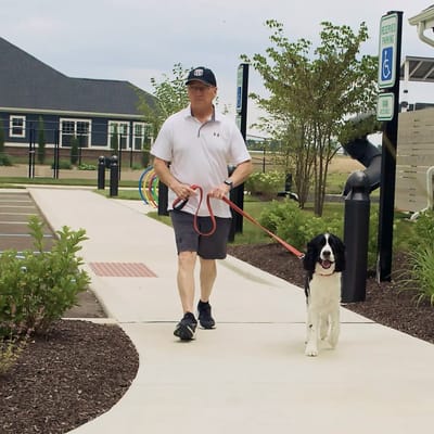 Resident walking a dog on a paved path outdoors