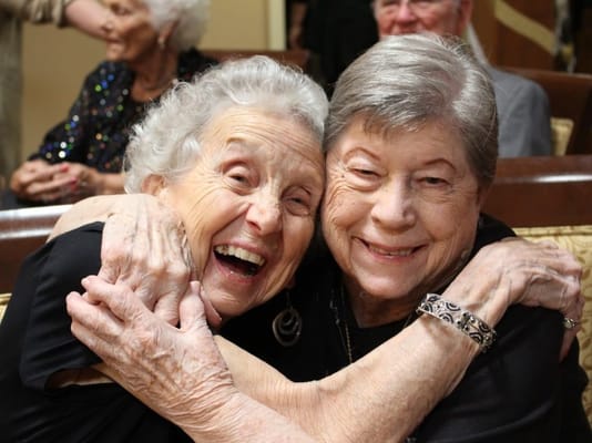 Two elderly women joyfully hugging each other