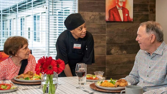 Dining area with a staff member serving residents food
