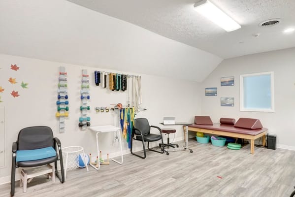A well-equipped therapy room with exercise equipment and seating.