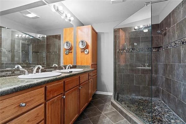 A modern bathroom featuring dual sinks and a glass shower enclosure.