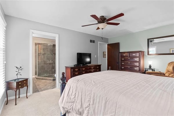 Spacious bedroom featuring a bed, dresser, and bathroom entrance.