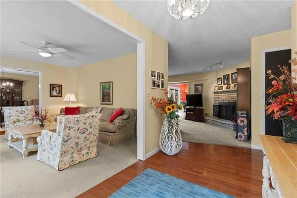 Bright entrance to a cozy living room with floral armchairs and a fireplace.