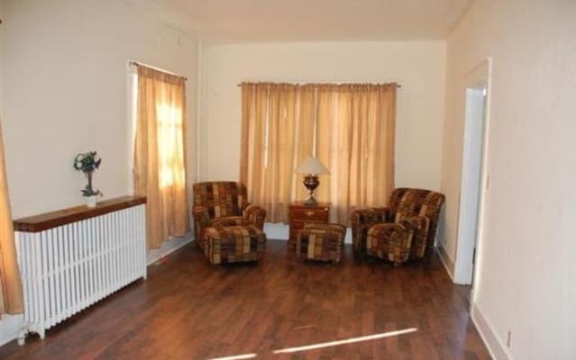 A cozy living room with two armchairs, a lamp, and a radiator.
