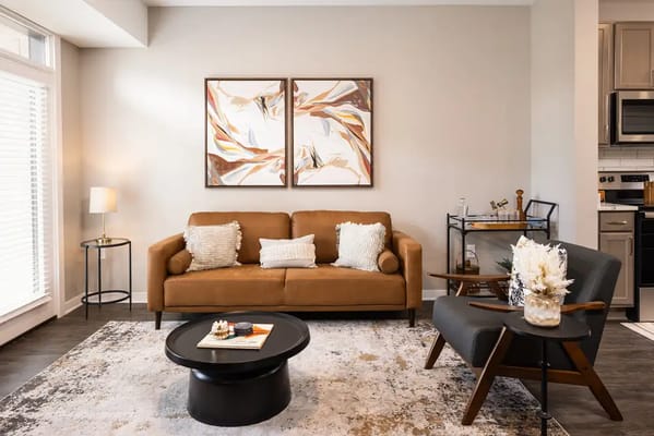 A cozy living room featuring a brown sofa, a coffee table, and decorative art.