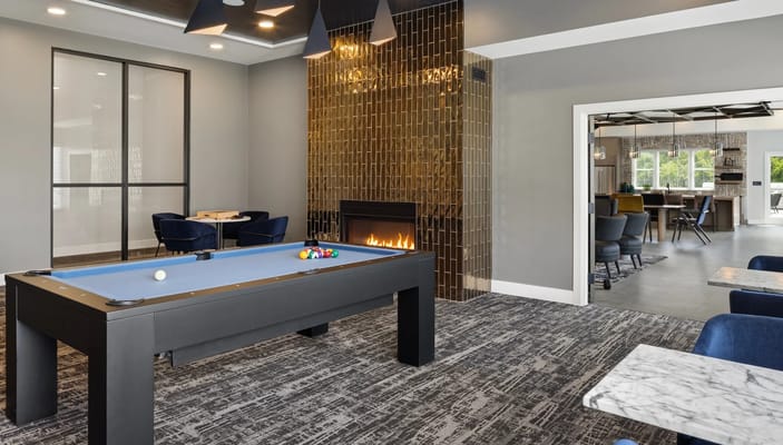 A billiards table in a stylish lounge area with a fireplace.