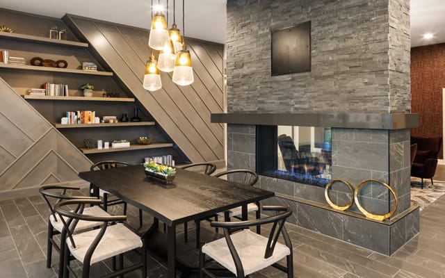Cozy lounge area with a black dining table, stone fireplace, and book shelves.