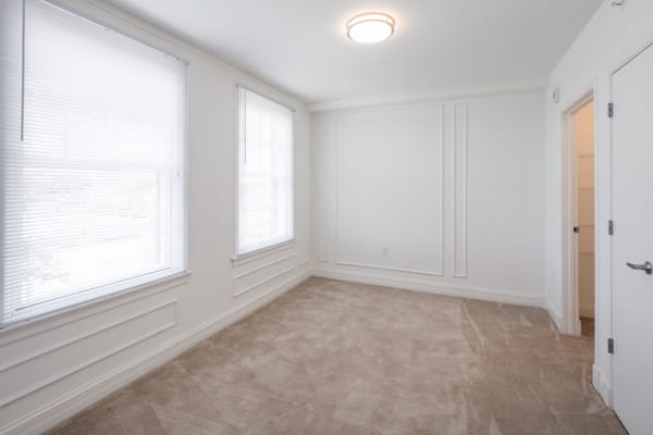Neutral interior of a resident room with carpet and windows