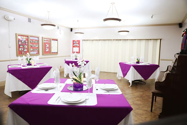 A dining room with purple tablecloths and elegant table settings.
