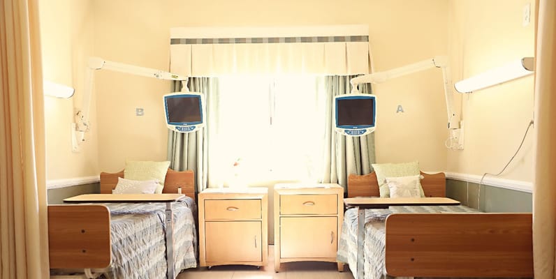 Brightly lit patient room with two beds and monitors