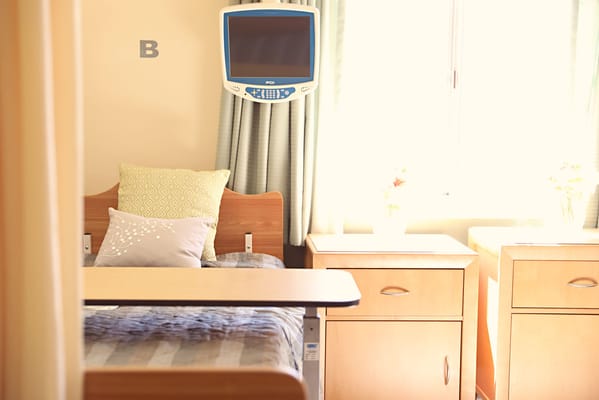 Well-lit patient room with adjustable bed and small tables.