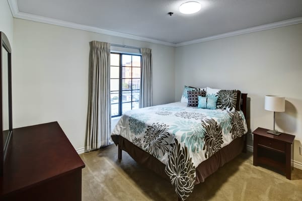 A cozy bedroom with a bed, decorative pillows, and a window