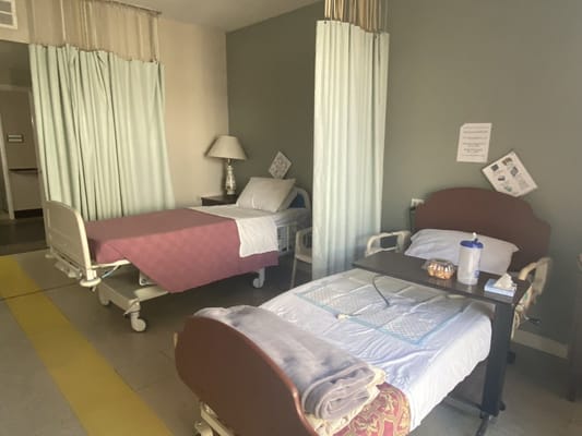 Two beds in a shared patient room with curtains for privacy