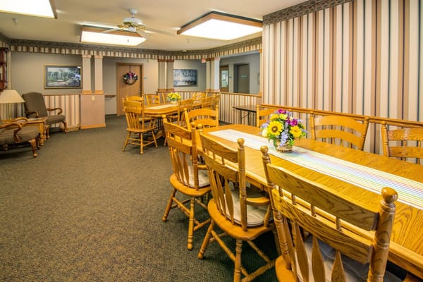 Bright dining area with wooden tables and chairs adorned with flower arrangements.