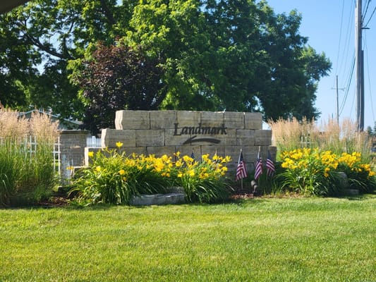Landmark sign with flowers and flags in the foreground