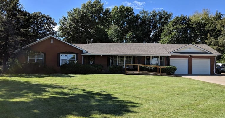 Exterior view of Keepsake Kottage with a green lawn and trees