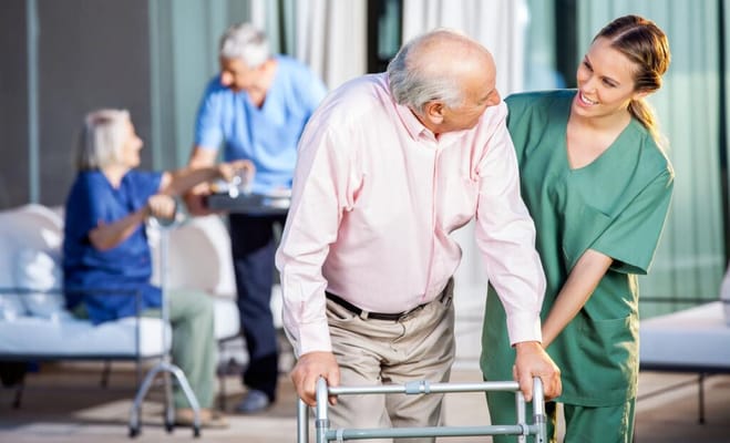 A caregiver assists an elderly man using a walker in a senior living facility.