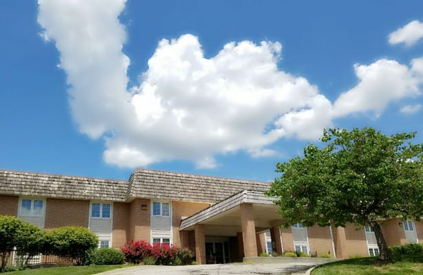 Exterior view of Arbor Court Retirement Community under a blue sky