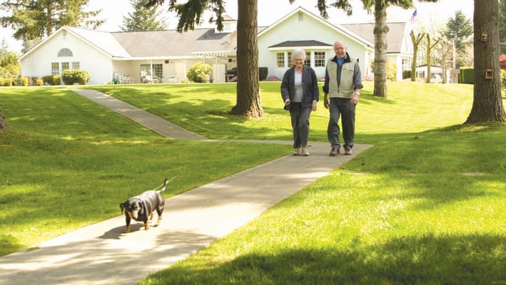Two residents walking with a dog on a pathway