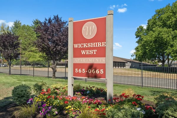 Sign for Wickshire West Senior Apartments surrounded by flowers