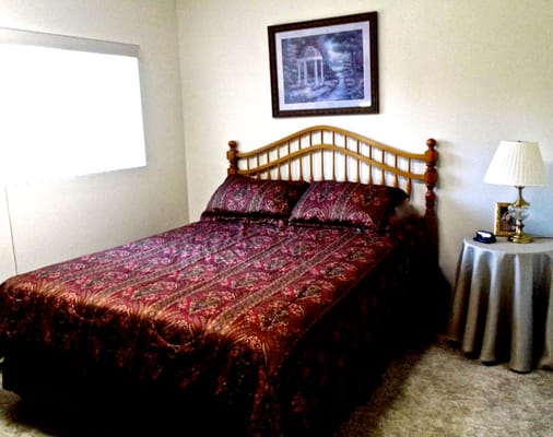 Interior view of a resident bedroom with a bed and lamp