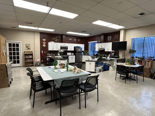 Interior view of a common area with tables and kitchen appliances