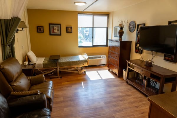A well-furnished private resident room with a bed and seating area