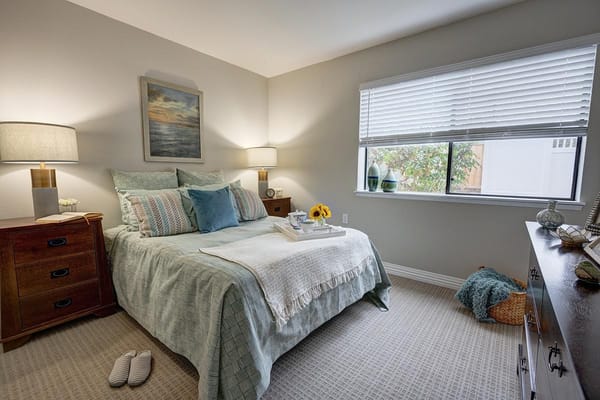 A well-furnished bedroom with a bed, lamps, and decorative accessories.