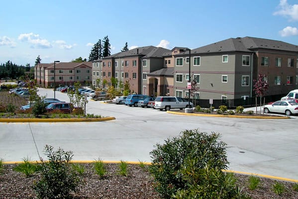 Exterior view of Sunset Garden Senior Living Apartments with parking area