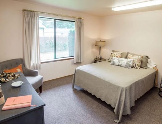 A warm and inviting bedroom featuring a bed, desk, and window.