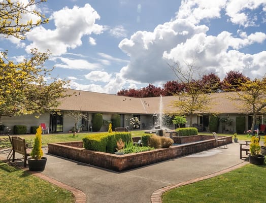 A serene garden featuring a fountain and landscaped plants at Village Concepts of Marysville.