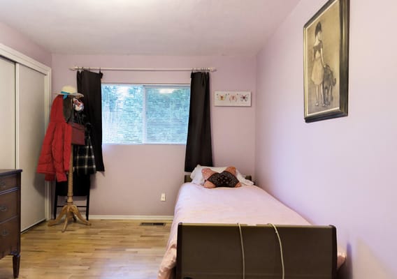 A cozy bedroom featuring a bed and a mannequin dressed in clothing.